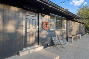 A building with a dark facade, a front door with a wreath, and a bench outside. - Wilderness Haven with Hot Tub in Franktown (Franktown)