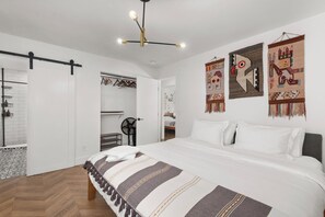 Un dormitorio con una cama, una lámpara colgante y decoración en la pared.