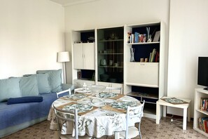 Un salon avec une table ronde, un canapé, une bibliothèque et un téléviseur.