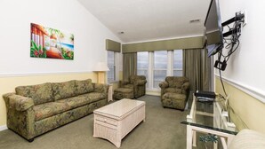 A living room with a sofa, armchairs, a coffee table, and a TV mounted on the wall. - Two Bedroom, Ocean View, Luxury Condo, North Myrtle Beach, SC 3928149 (North Myrtle Beach)