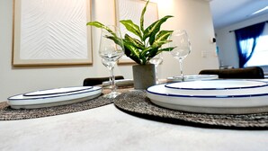 A dining table set with plates, glasses, and a potted plant. - SōLE Villa #2|Elegant 2BR Retreat|Beach|Stargazing (Cocoa Beach)