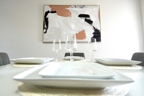 A dining table set with white plates, glasses, and a rectangular serving tray. - Villa Fiorō-Bold Luxury 2BR /River & Coastal Vibe (Cocoa Beach)