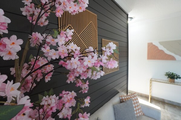 A room with a dark wooden wall, a decorative panel with geometric patterns, and a small plant on a side table. - Villa Fiorō-Bold Luxury 2BR /River & Coastal Vibe (Cocoa Beach)