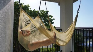 Un hamac suspendu aux balustrades d’un balcon, avec un sol en béton et une balustrade agrémentée d’un portail en métal.
