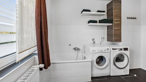 A laundry room with a washing machine, dryer, and a wooden cabinet above the dryer. - Nice home in Tossens with WiFi (Tossens)
