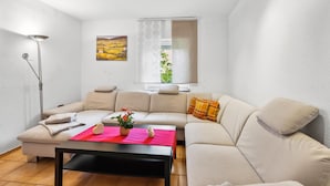 A modern living room with a beige sofa, a small table with a red cloth, and a floor lamp. - Nice home in Tossens with WiFi (Tossens)