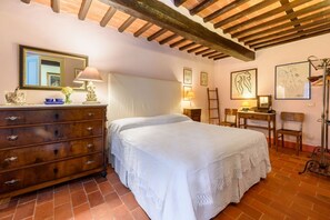 A bedroom with a bed, dresser, desk, chair, and artwork on the walls.