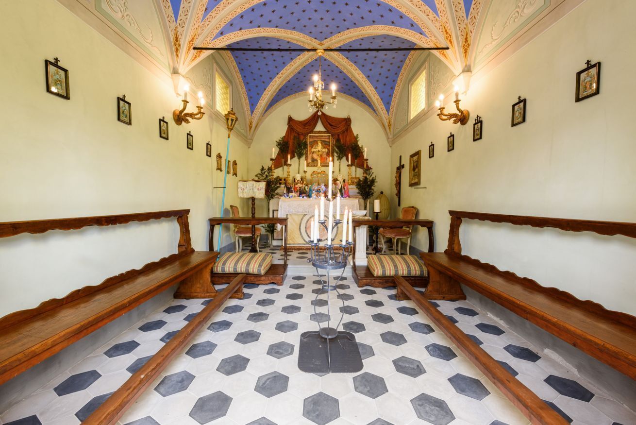 Interior de iglesia con suelo de baldosas hexagonales, bancos de madera, un altar central y un techo con diseño de estrellas azules.