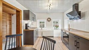 Una cocina moderna con suelo de madera, horno empotrado y un ventanal con vistas al verdor.