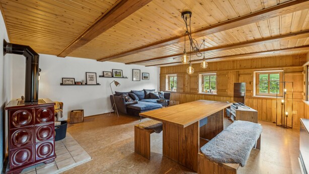 Un interior de madera acogedor con una mesa de comedor, sofá y una estufa empotrada.