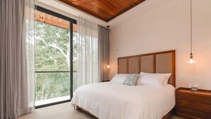 A bedroom with a large bed, wooden headboard, and a nightstand with a lamp.