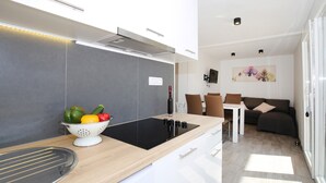 Une cuisine moderne avec une plaque de cuisson à induction noire, une passoire remplie de légumes et une bouteille de vin.