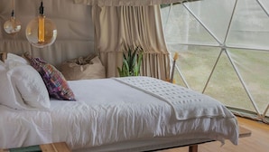 Ein gemütliches Zelt-Schlafzimmer mit Bett, Nachttisch und Blick ins Freie.