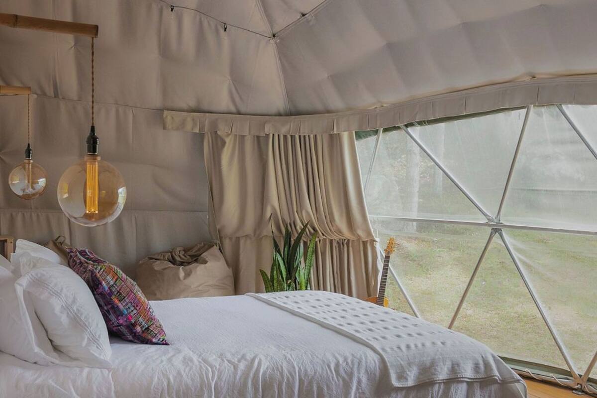 Ein gemütliches Zelt-Schlafzimmer mit Bett, Nachttisch und Blick ins Freie.