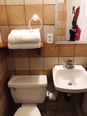 Une salle de bain équipée de toilettes, d’un lavabo et d’un porte-serviettes avec des serviettes pliées.