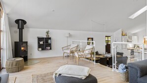 Una sala de estar moderna con chimenea de leña, mobiliario de mimbre y una mesa de comedor de vidrio.