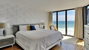 A modern bedroom with a large bed, nightstands, and a view of the ocean. - Edgewater Tower III by Resort Collection (Panama City Beach)