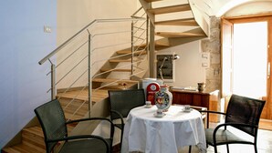 Ein Essbereich mit einem runden Tisch, vier Stühlen, einer Treppe und einem Küchenbereich im Hintergrund.
