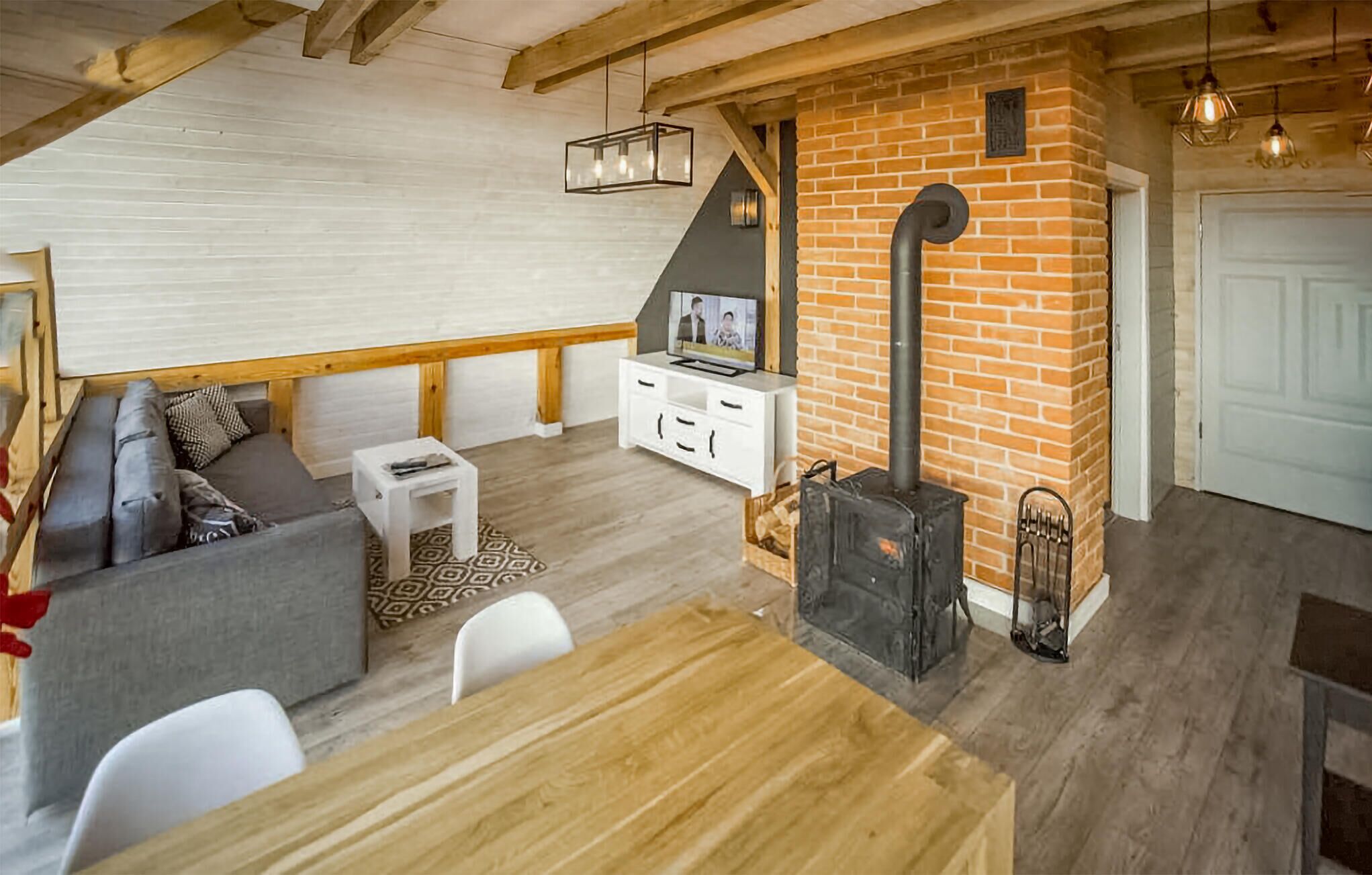 Een gezellige woonkamer met een open haard, een bank, een televisie en een eethoek.