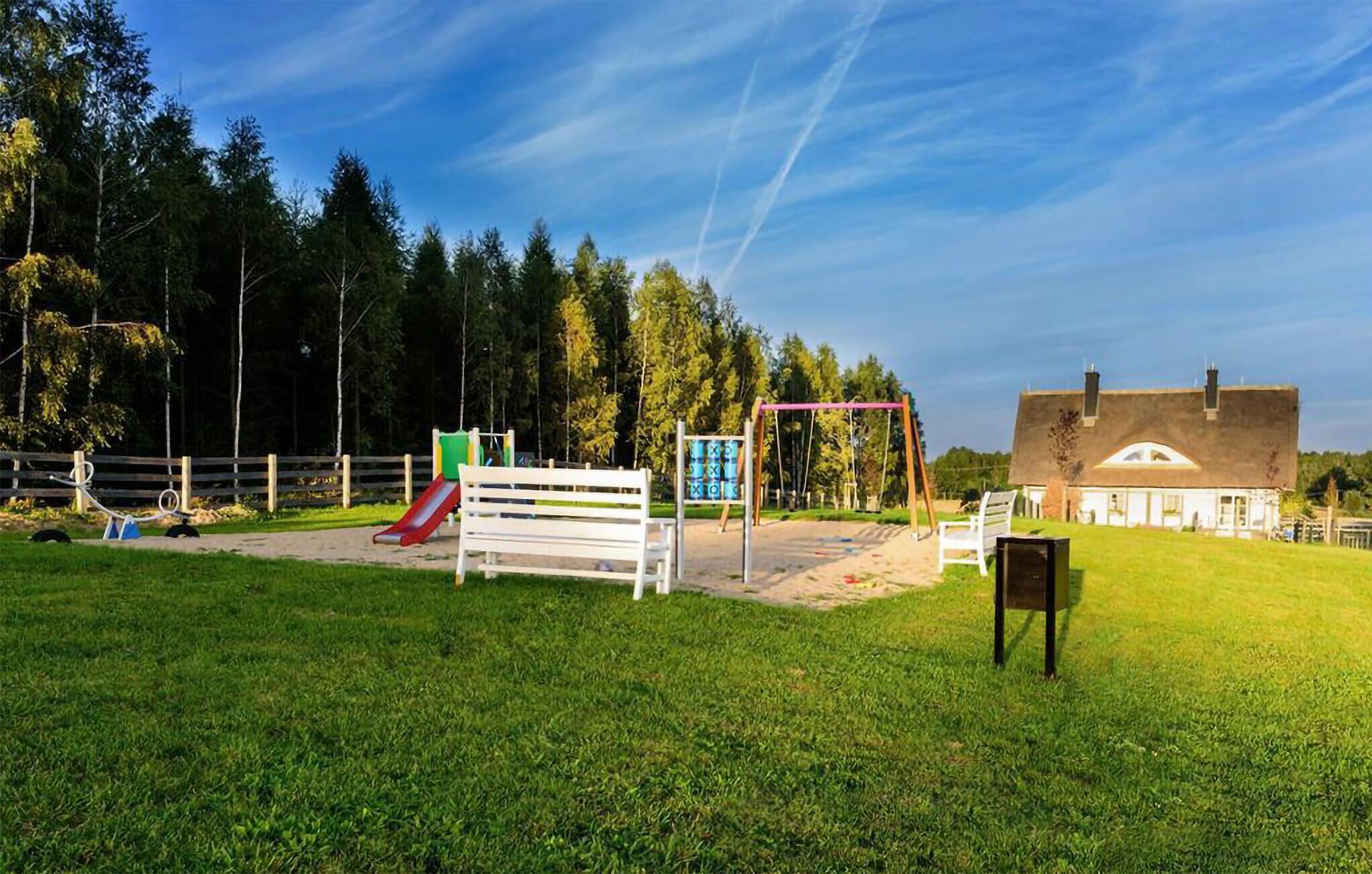 Ein Spielplatz mit Rutsche, Schaukeln und einer Bank.