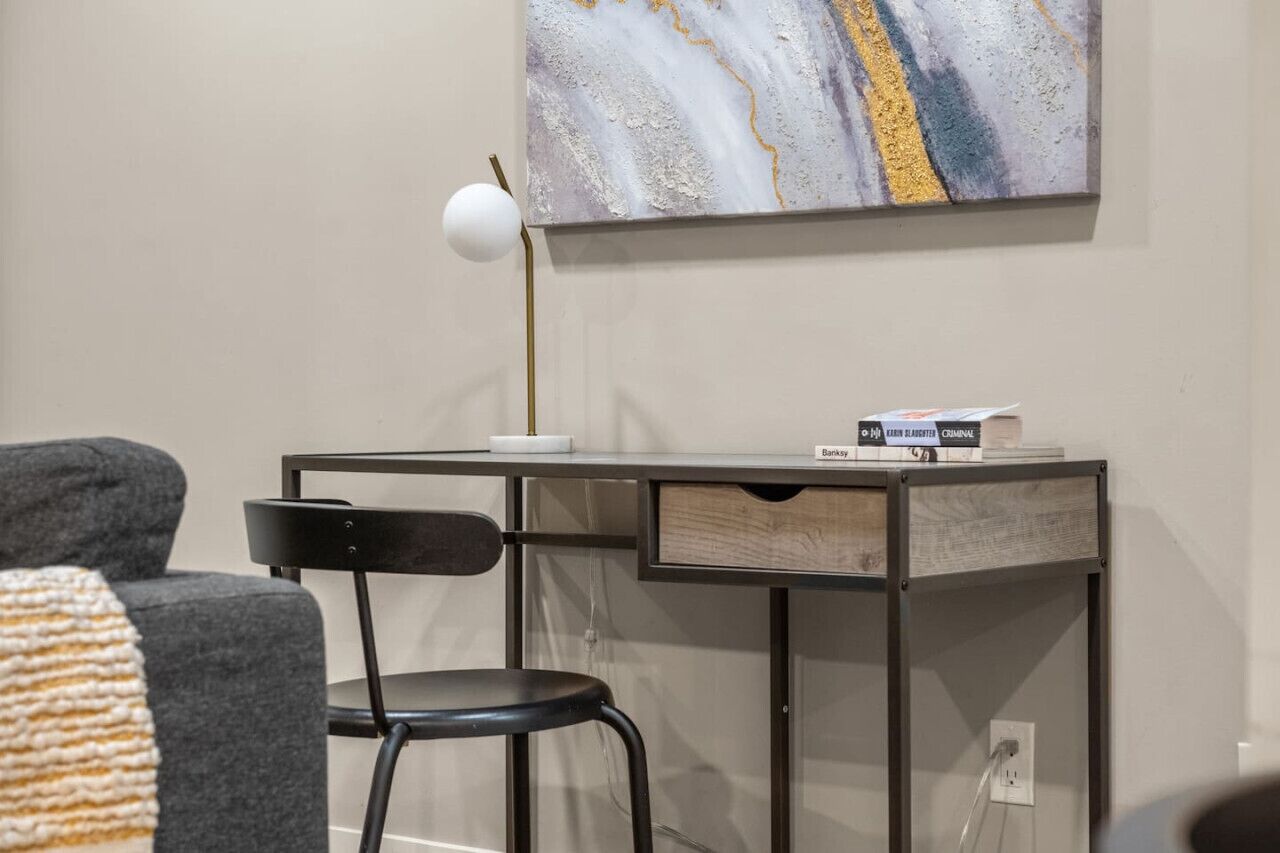 A modern office space with a desk, chair, and a large abstract painting on the wall.