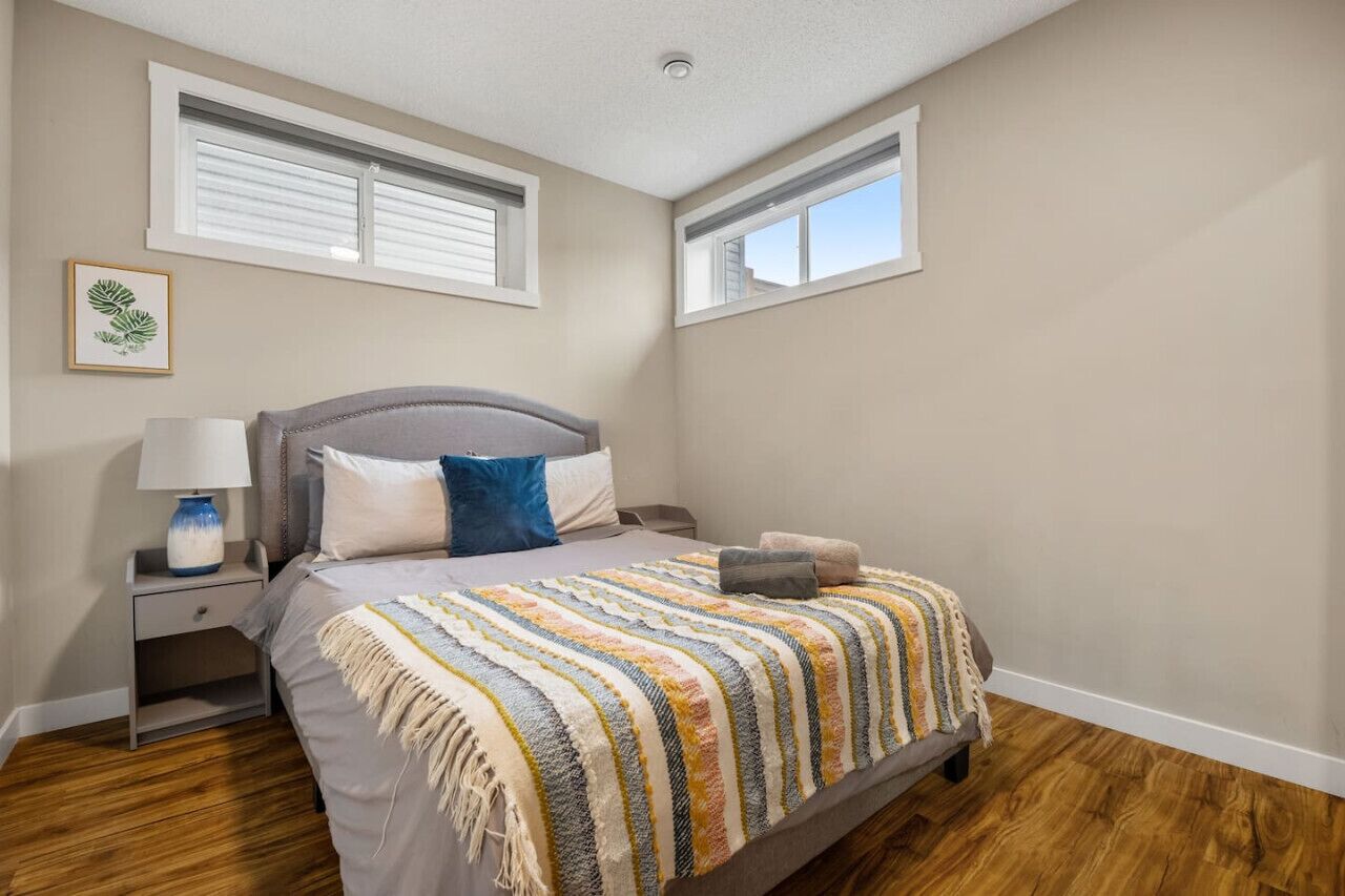 A bedroom with a bed, nightstands, a lamp, a window, and a framed picture on the wall.