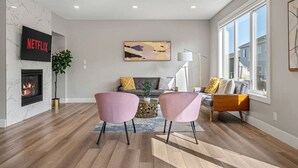Una sala de estar moderna con chimenea, un televisor montado en la pared y un amplio ventanal que proporciona luz natural.