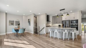 Una cocina moderna con una isla central, taburetes de bar y un comedor con mesa y sillas.