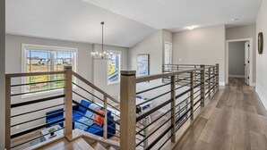 Amplia sala de estar con escalera, vista al exterior y una lámpara moderna.