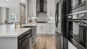 Una cocina moderna con armarios blancos, electrodomésticos de acero inoxidable y una isla central.