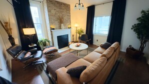 A living room with a sofa, armchairs, a coffee table, a fireplace, and a large window.