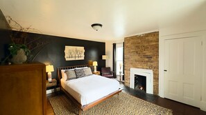 Une chambre à coucher comprenant un lit, des tables de chevet, une lampe, une chaise, une cheminée et un mur au décor texturé.
