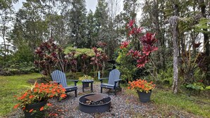 An outdoor seating area with Adirondack chairs, a fire pit, and potted plants. - Cozy Volcano Cottage  (Volcano)