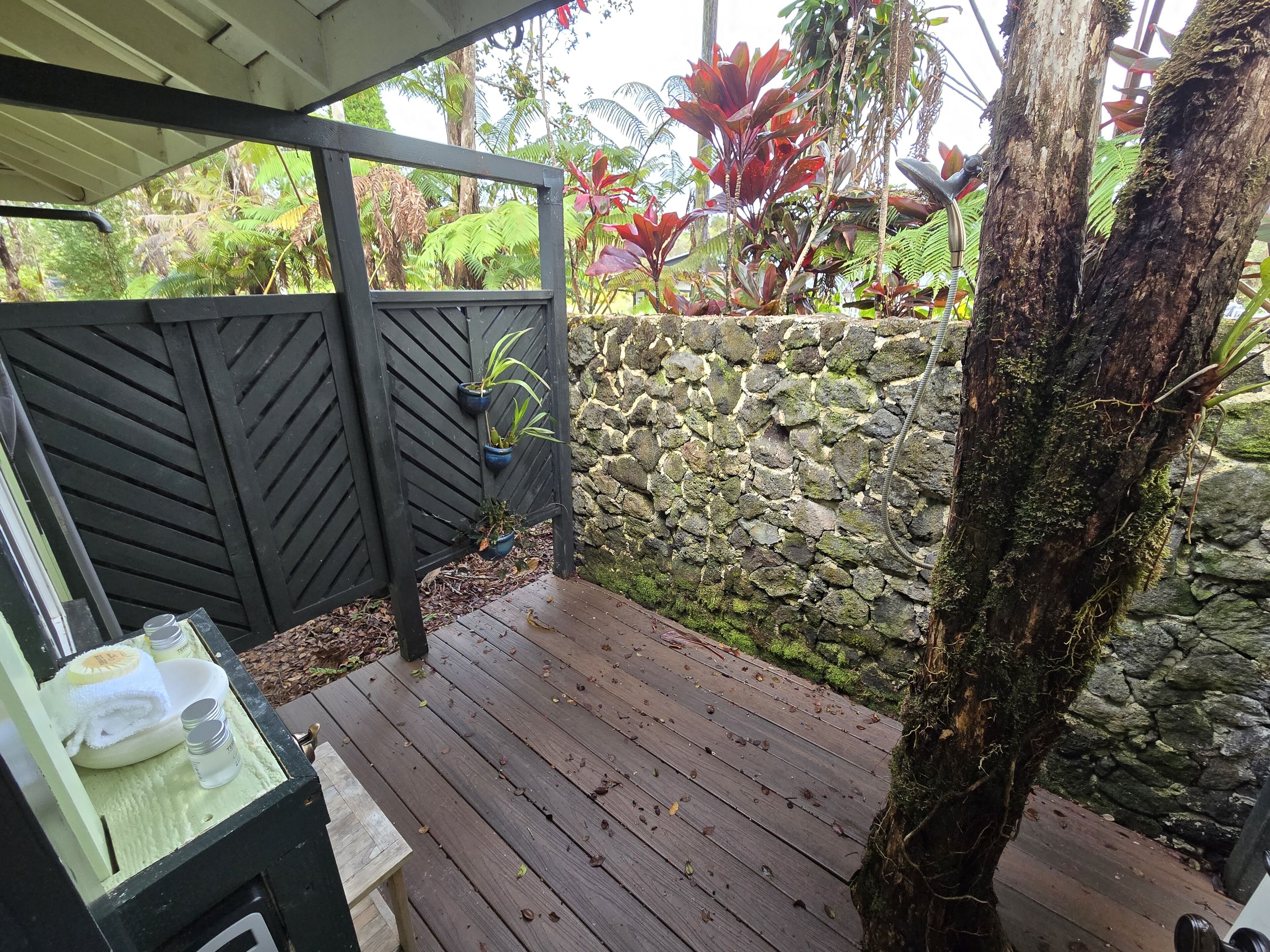 A wooden deck with a stone wall and a black metal gate.