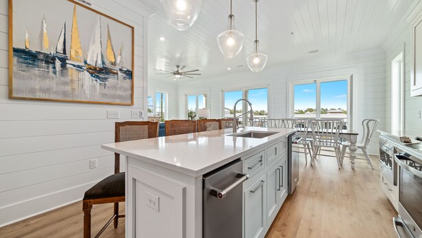 Une cuisine moderne avec des meubles blancs, un îlot central et des luminaires suspendus.