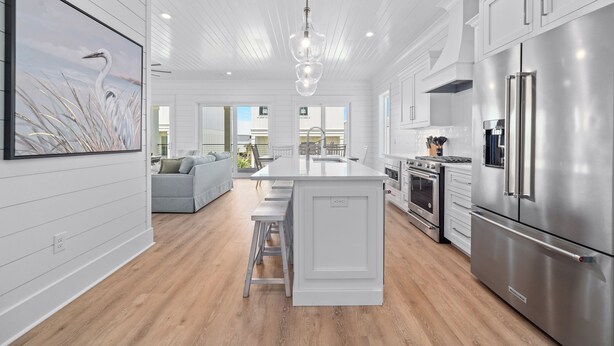 Une cuisine moderne avec des meubles blancs, des appareils en acier inoxydable et un îlot central.