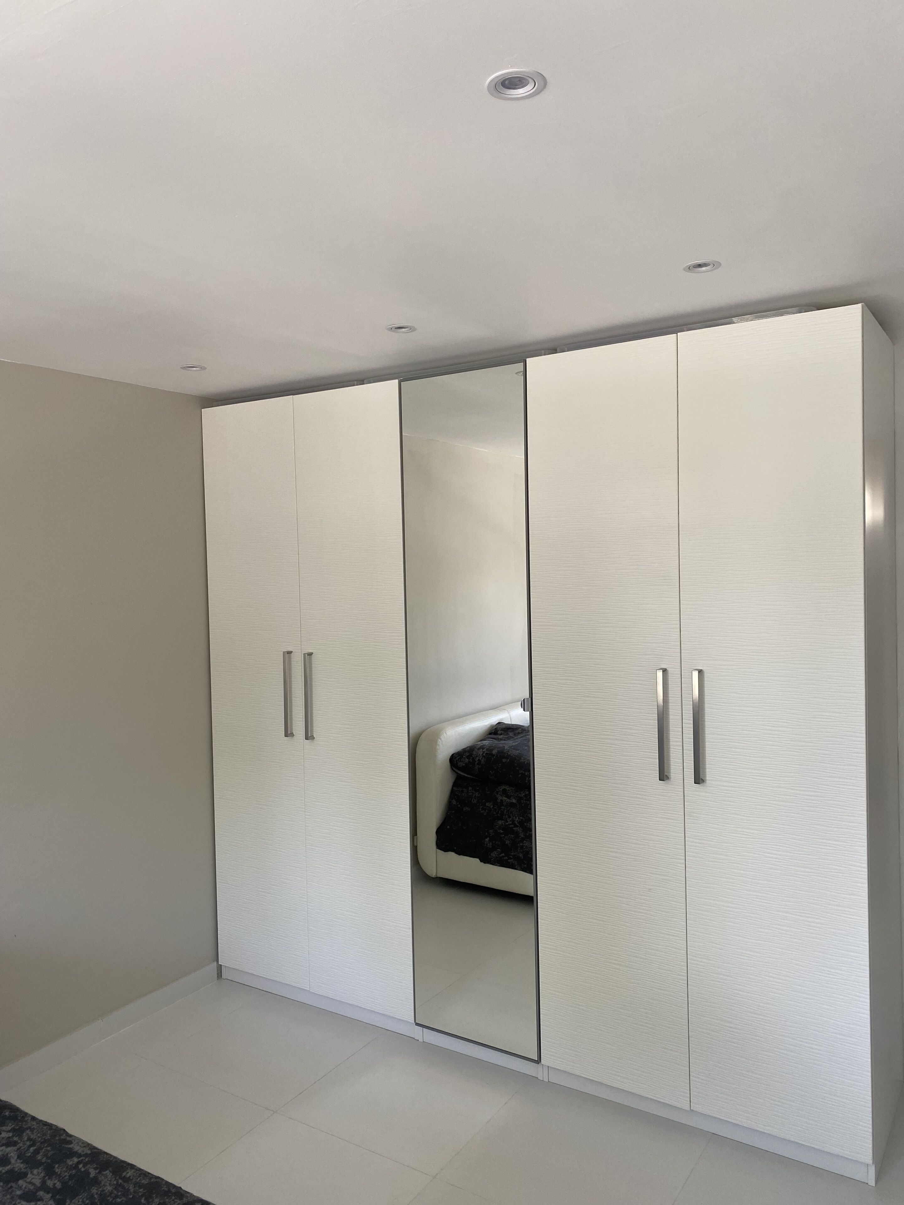 Een moderne slaapkamer met een ruime garderobe, een bed en een plafondlamp.
