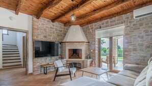 A spacious living area with a stone fireplace, a flat-screen TV, and a comfortable seating arrangement. - Gorgeous home in Cabrunici (Cabrunici)