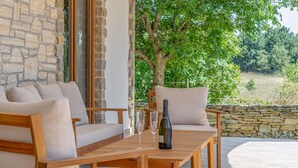 A wooden outdoor seating area with a stone wall, a bottle of wine, and glasses on a table. - Gorgeous home in Cabrunici (Cabrunici)