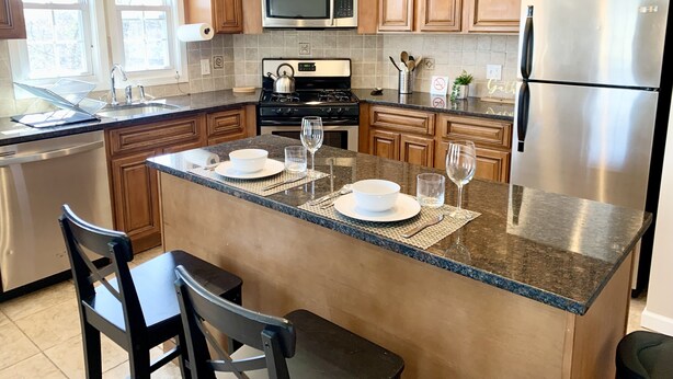 A modern kitchen with wooden cabinets, stainless steel appliances, and a granite countertop.