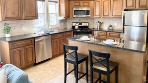 A modern kitchen with wooden cabinets, stainless steel appliances, and a central island with bar stools.