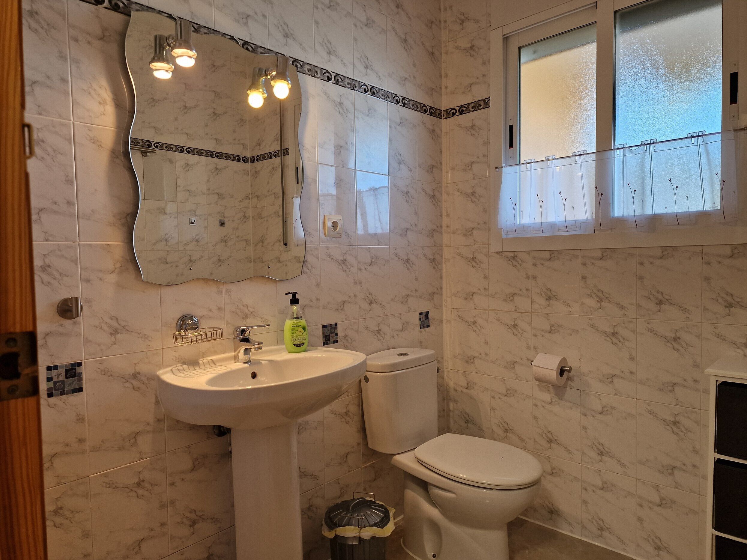 Une salle de bain équipée d’un lavabo, de toilettes et d’un miroir avec éclairage.