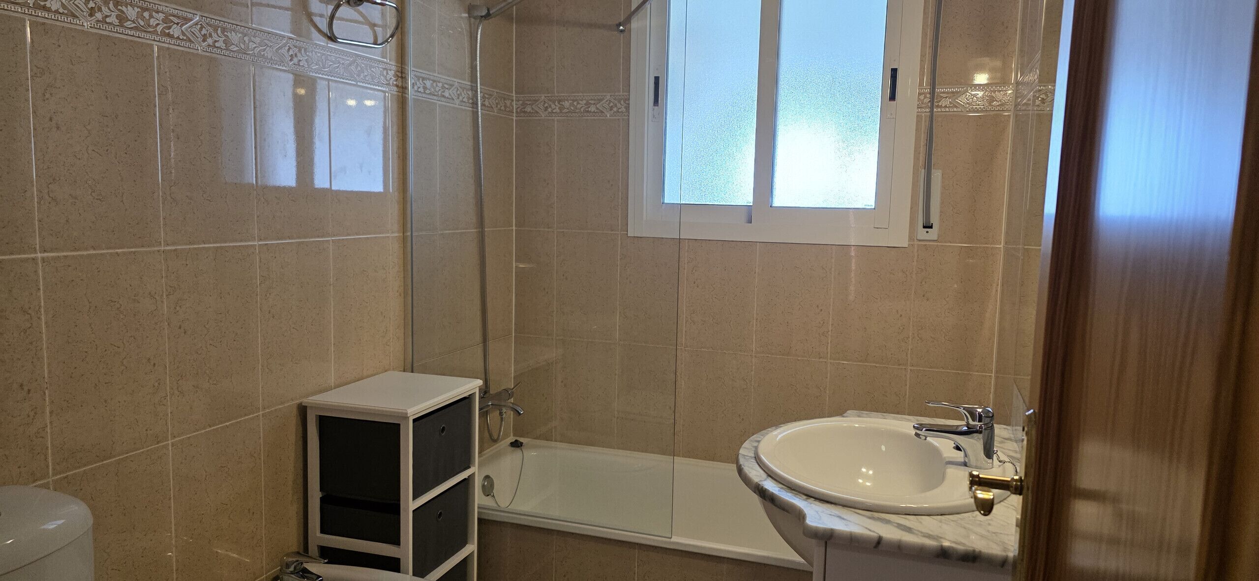 Ein Badezimmer mit Dusche, Badewanne, Waschbecken und einem kleinen Schrank.