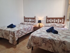 Ein Hotelzimmer mit zwei Einzelbetten, jeweils mit blumigem Bettbezug und gerollten Handtüchern.