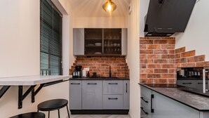A compact kitchen with grey cabinets, a herringbone-patterned backsplash, and a black countertop. - Doki Studio Stocznia by Grand Apartments (Gdansk)