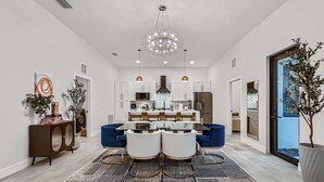 A modern kitchen with white cabinets, a central island, and a chandelier.