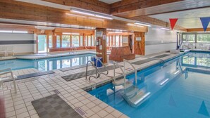 Ein Innenpool mit Holzbalken, Fliesenböden und großen Glaswänden.