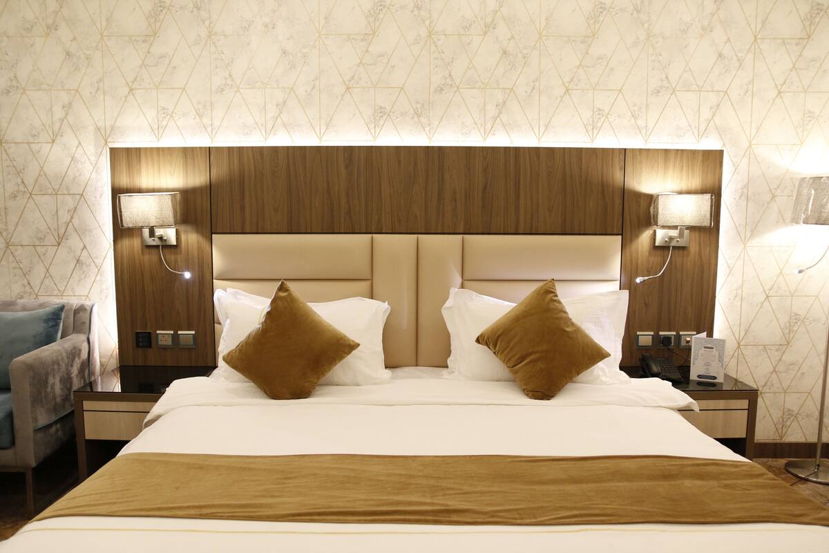 Ein Hotelzimmer mit einem großen Bett, zwei Nachttischen, einer Lampe und einem an der Wand montierten Fernseher.