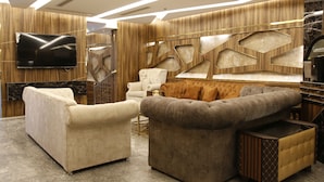 Ein modernes Wohnzimmer mit großem Flachbildfernseher, komfortablen Sofas und einer Wand mit geometrischen Mustern.