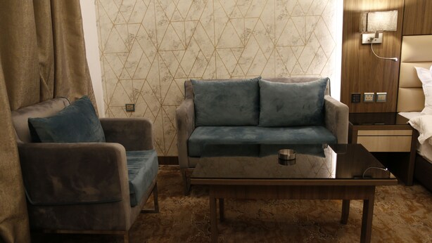 A hotel room with a sofa, armchair, and a small table. - Dan Golden Hotel & Lounge (Madinah)